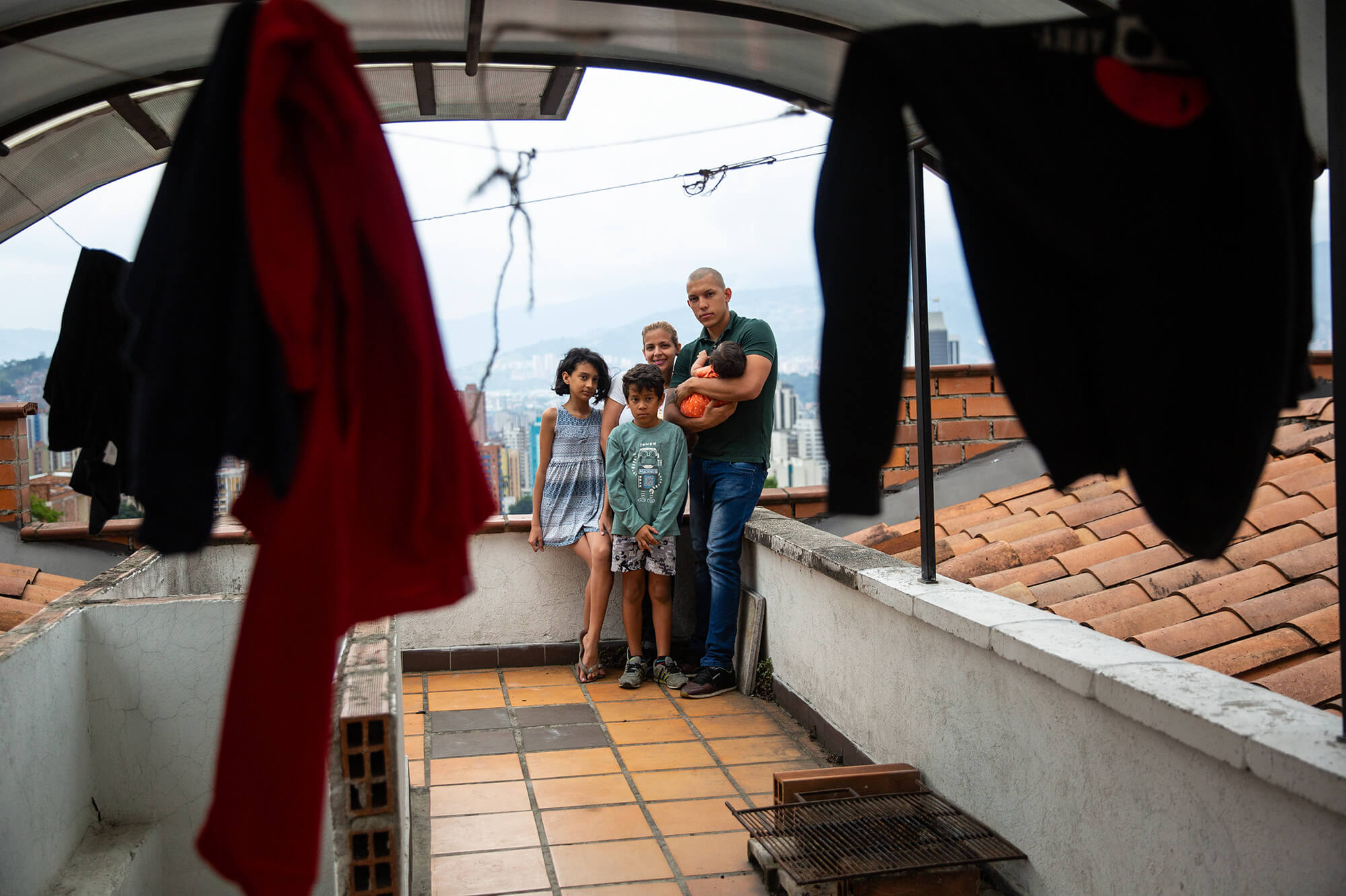 A family is seen on the roof of their apartment through hanging laundry