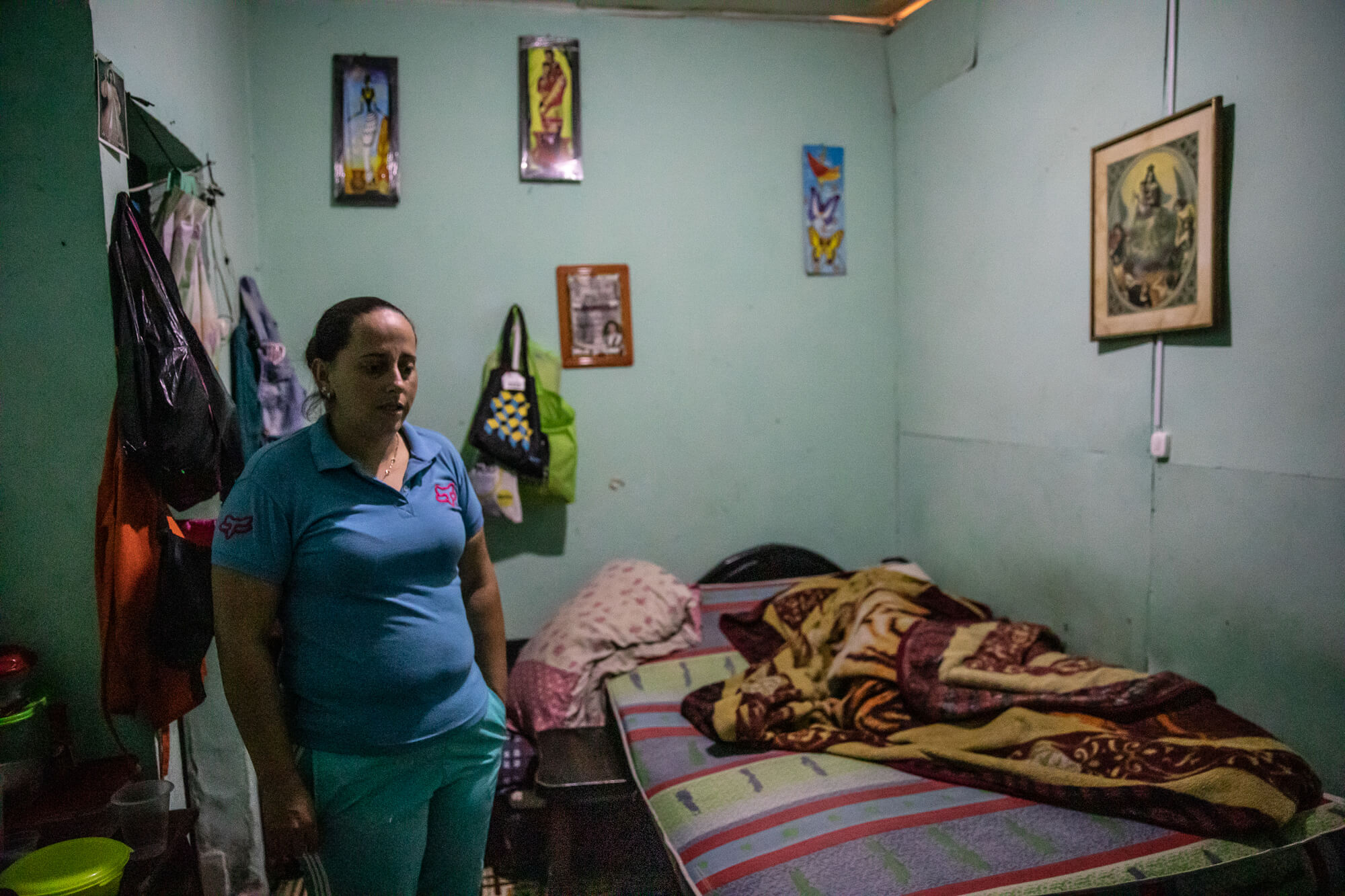 A woman wearing a blue shirt looks down over her small rented room
