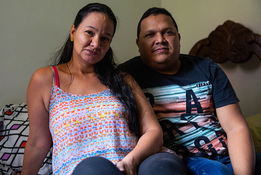 A couple sits together on their bed