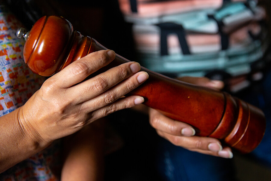 A pepper grinder is held by two pairs of hands