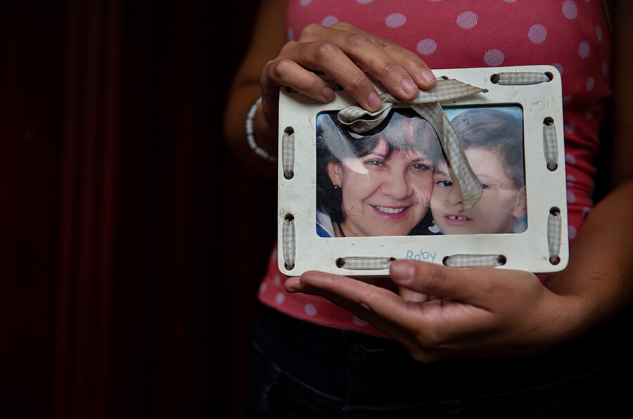 A woman holds a framed photograph of her family members