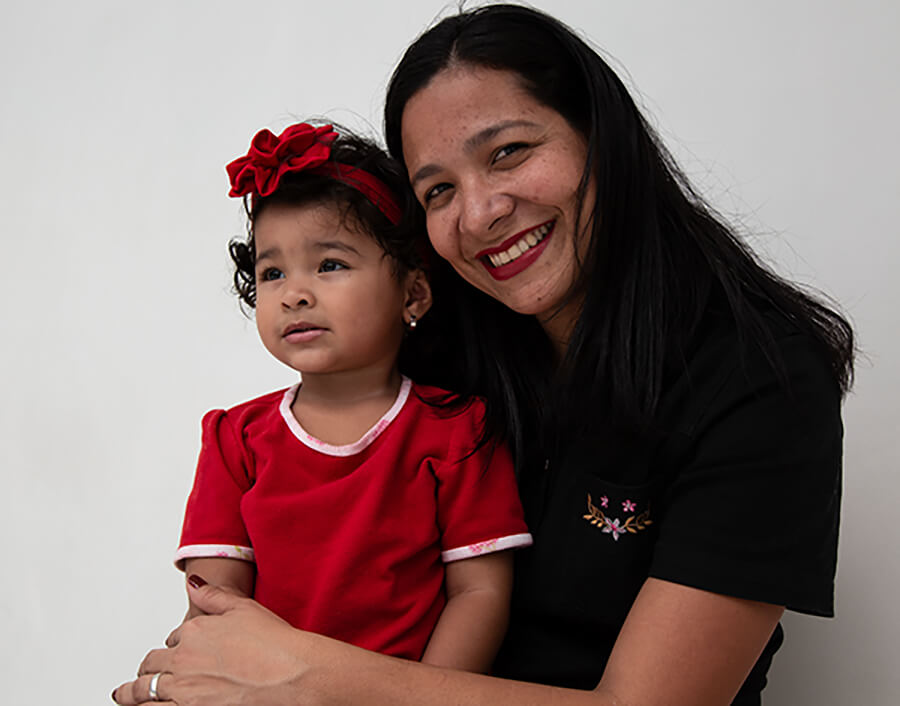 A smiling woman holds her daughter in her lap